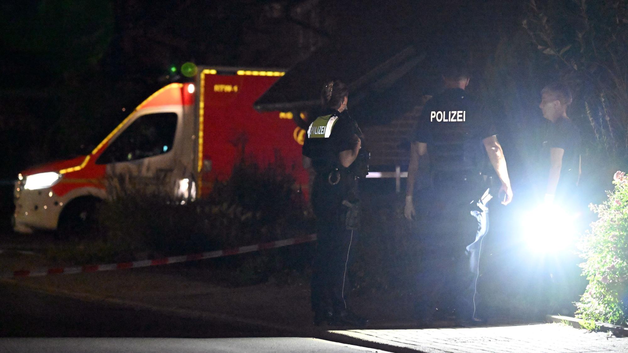 Polizisten stehen an einem gesperrten Bereich und sprechen mit einer Anwohnerin (Symbolfoto).