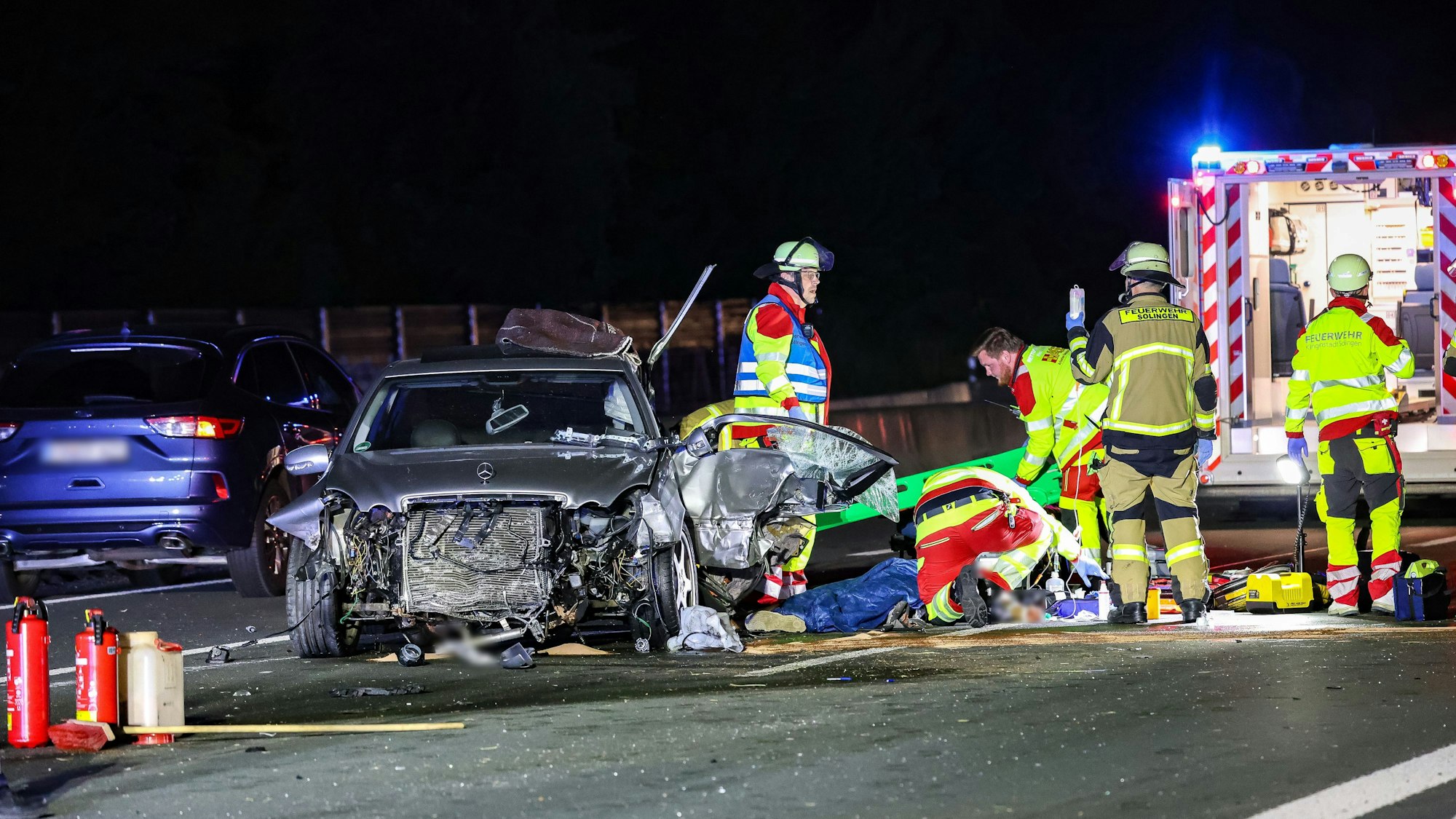 Eine verletzte Person wird neben einem zerstörtem Unfallfahrzeug behandelt. Bei dem Zusammenstoß mehrerer Fahrzeuge auf der A3 wurden zwei Fahrer schwer verletzt, einer von ihnen lebensgefährlich.
