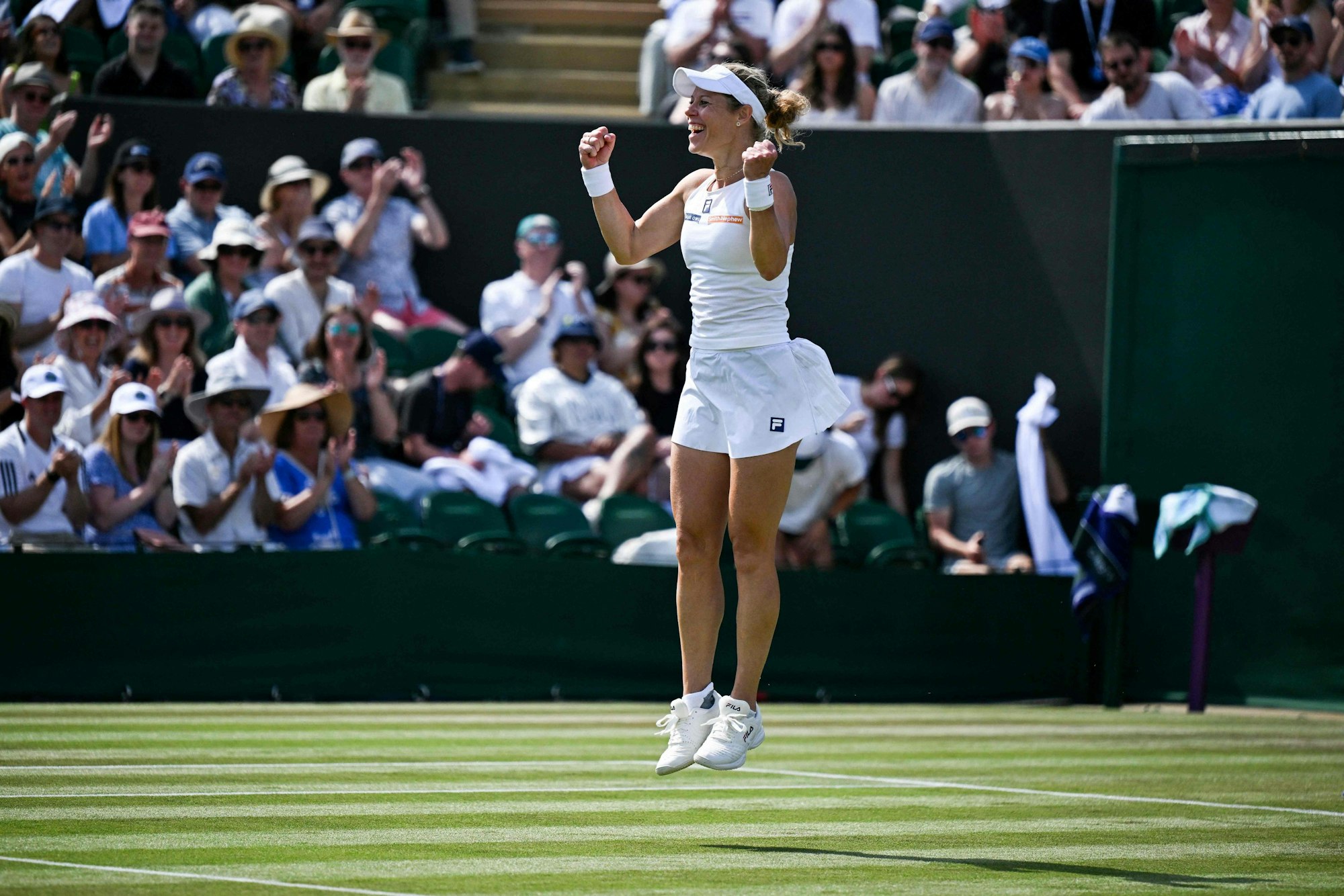 Laura Siegemund spring vor Freude auf dem Rasen von Wimbledon in die Höhe.