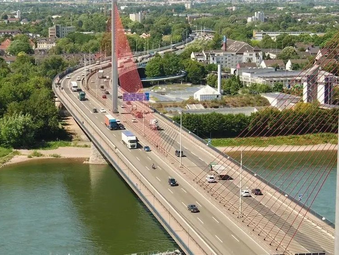 Autos und Lkw fahren über eine Brücke, die über einen Fluss führt.