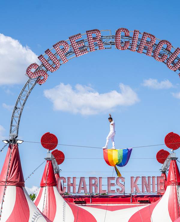 Der Hochseilartist David Ruiz vom Zirkus Charles Knie balanciert auf einem Seil über dem Zirkuszelt, wo eine Regenbogenfahne aus Protest hängt.