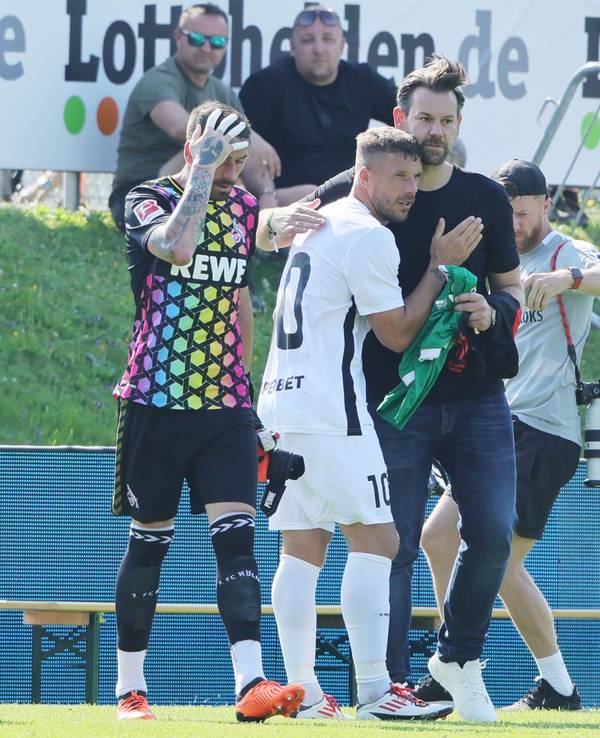 Lukas Podolski und Thomas Kessler umarmen sich auf dem Platz.