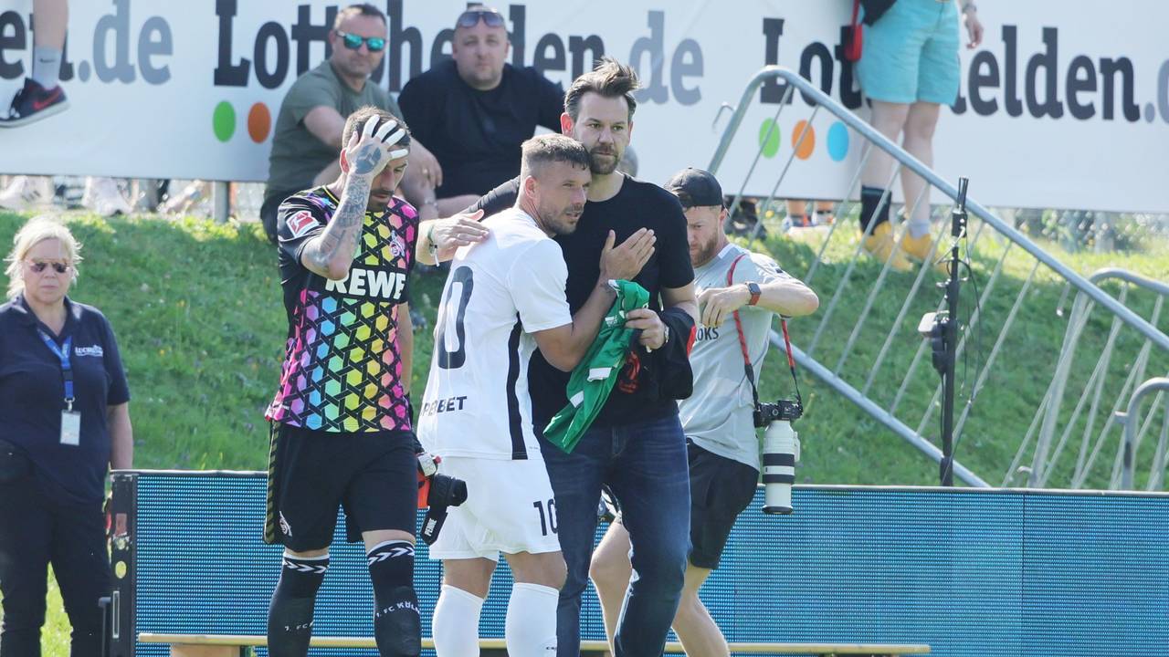Lukas Podolski und Thomas Kessler umarmen sich auf dem Platz.