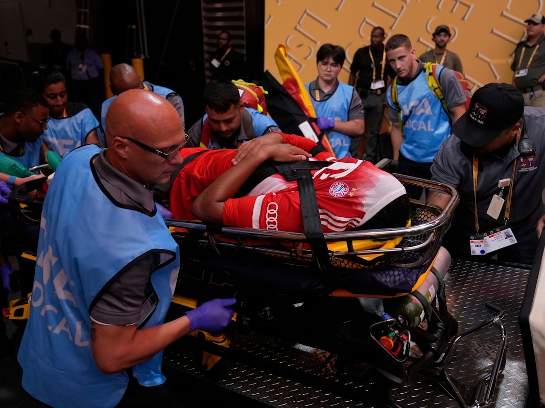 Jamal Musiala zieht sich, mutmaßlich schwer verletzt, das Trikot über den Kopf. Der Bayern-Star verlässt das Spielfeld auf einer Trage.