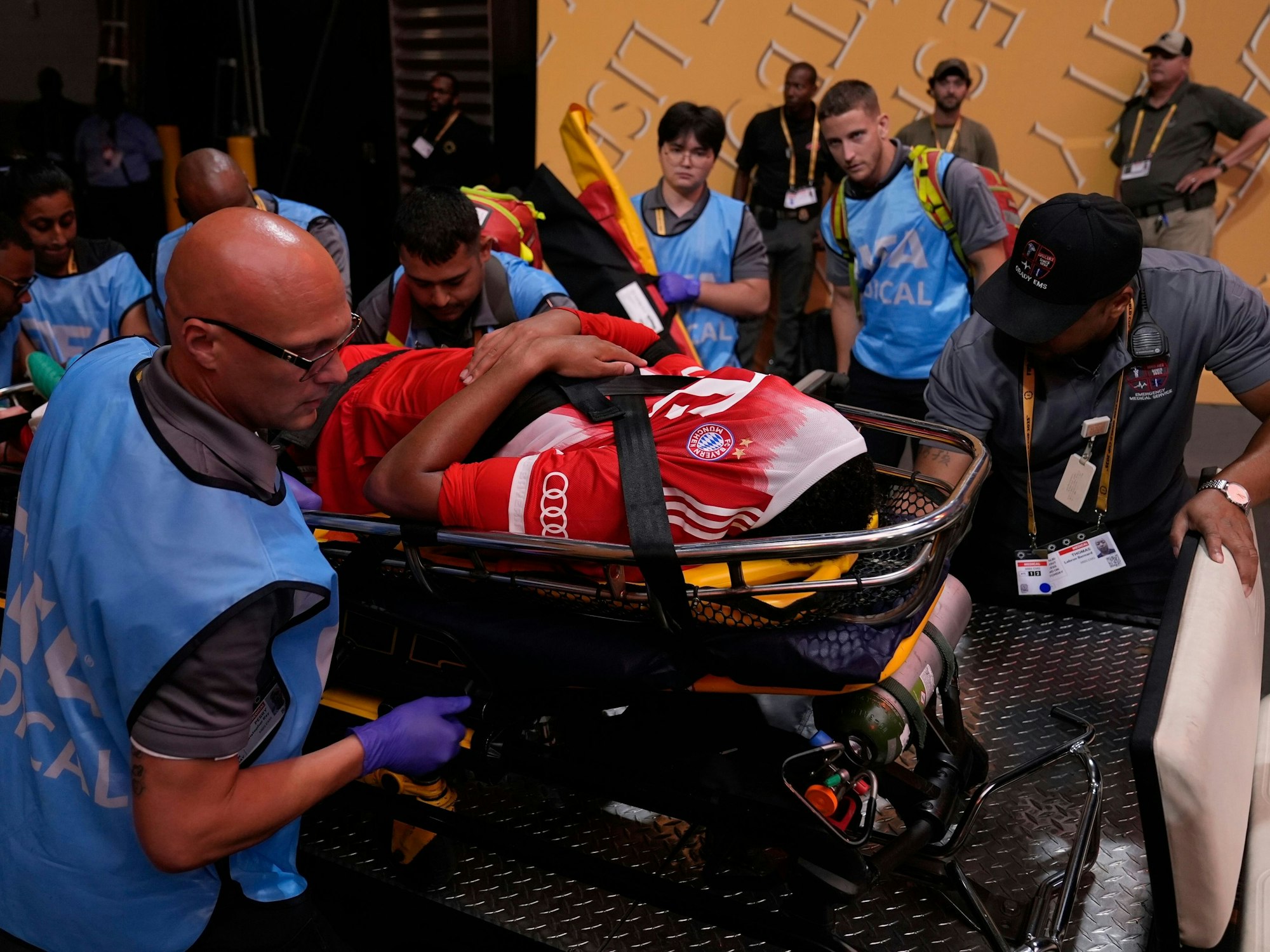 Jamal Musiala zieht sich, mutmaßlich schwer verletzt, das Trikot über den Kopf. Der Bayern-Star verlässt das Spielfeld auf einer Trage.