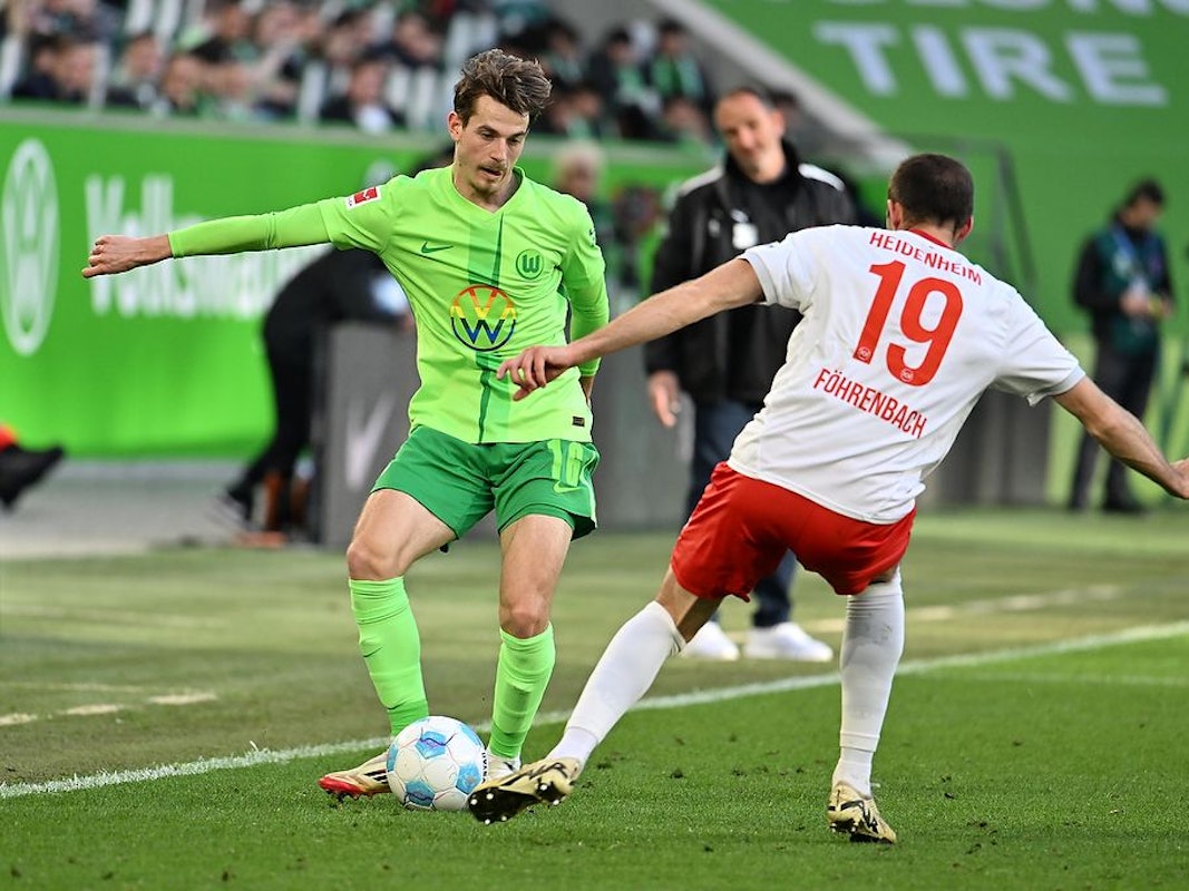 Wolfsburgs Jakub Kamiński (l) spielt gegen Heidenheims Jonas Föhrenbach.