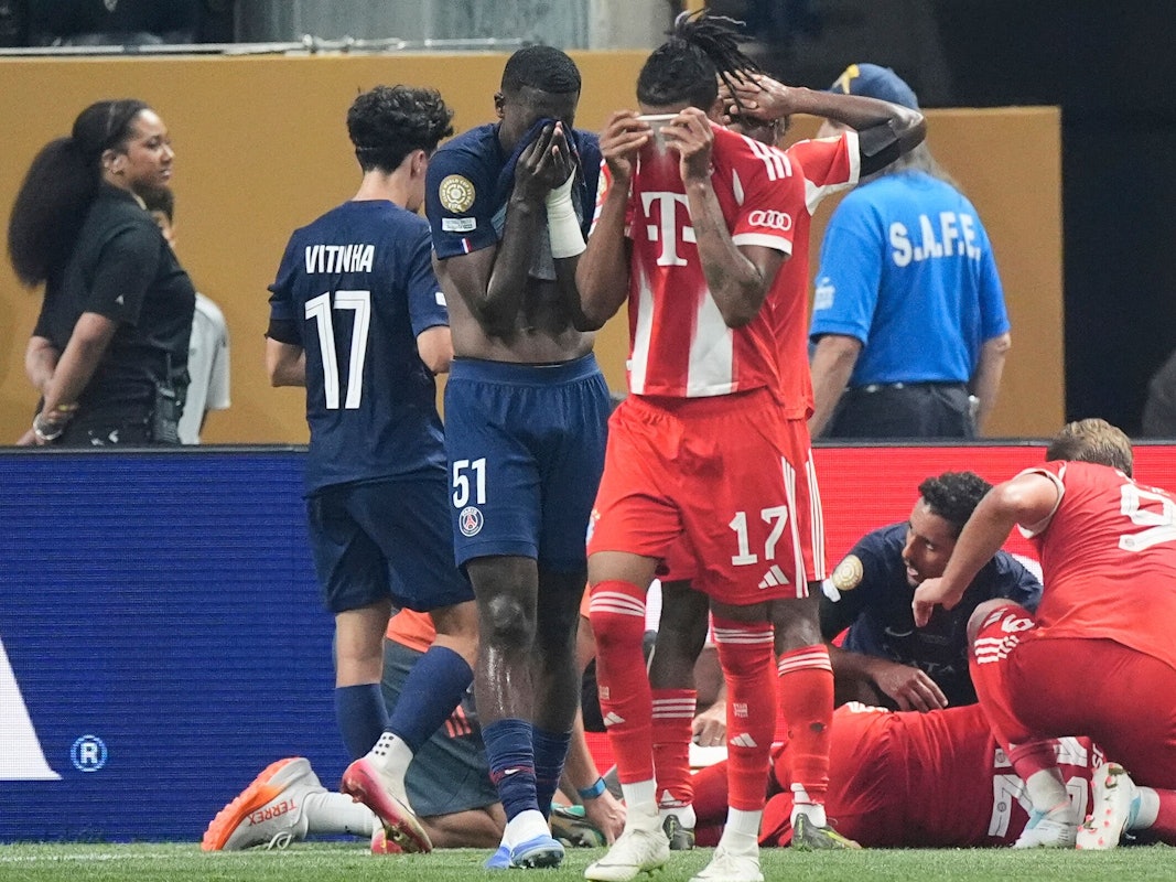 Bayern Münchens Michael Olise und Willian Pacho von Paris Saint-Germain bedecken ihr Gesicht, während Jamal Musiala verletzt am Boden liegt.