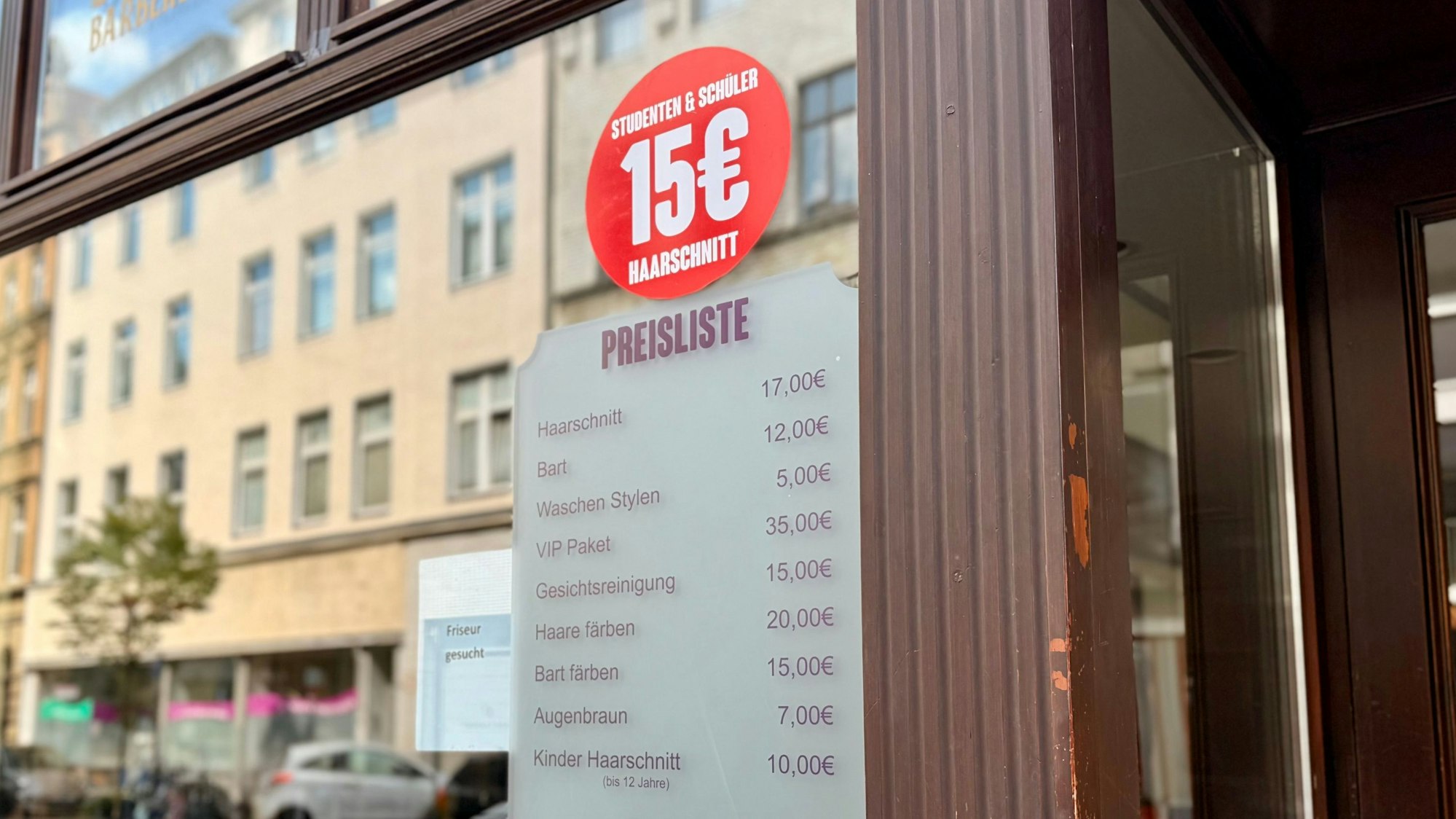Schaufenster eines Barbershops, zu sehen ist eine Preisliste. Der Herrenhaarschnitt wird für 17 Euro gelistet, Schüler und Studierende zahlen 17 Euro.