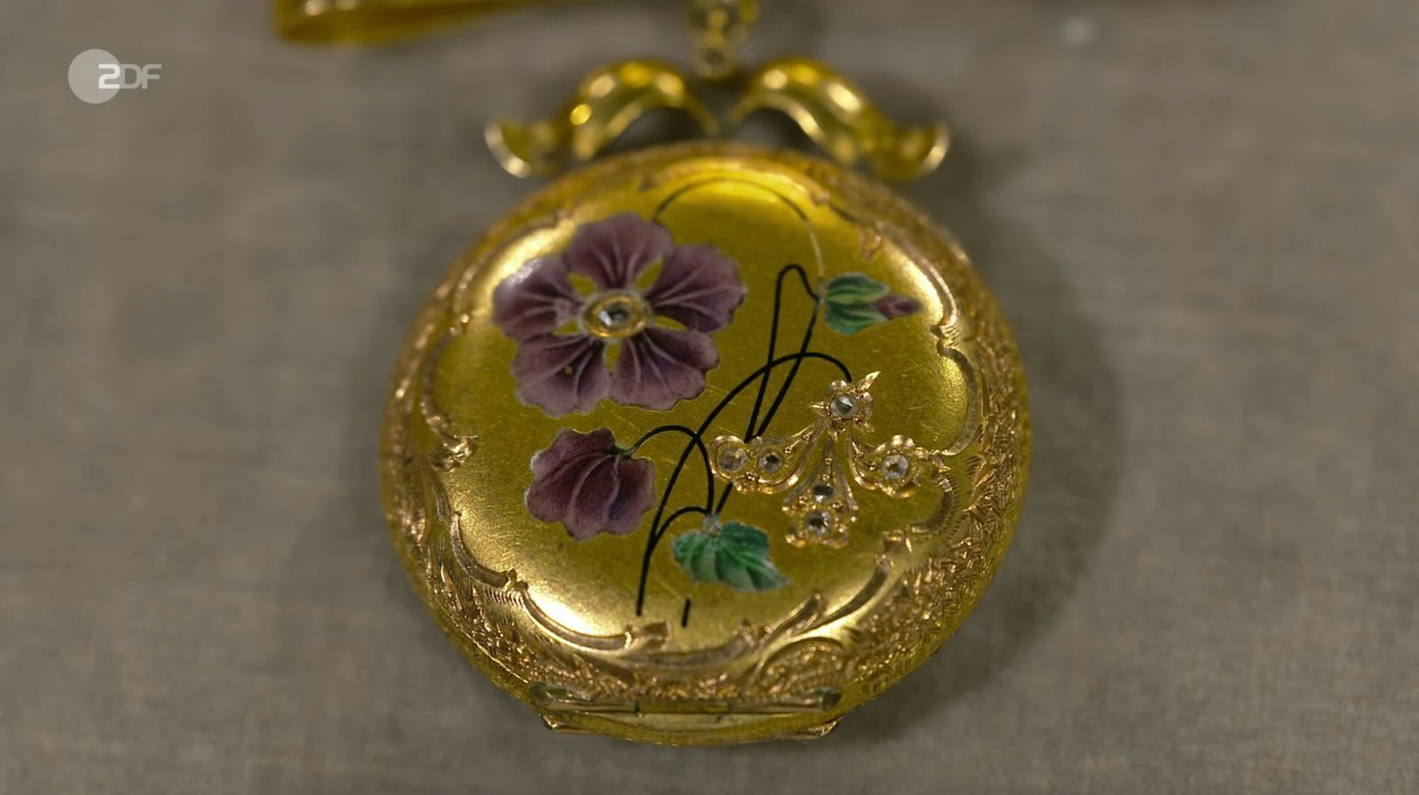 Heide Rezepa-Zabel zufolge handelte es sich bei dem Medaillon um eine Mariage aus einem leeren Uhrwerk aus den 1950er Jahren und einer Schleife aus den 1910er Jahren. Für den Schmuck aus 585er und 750er Gold mit feiner Emaille lag der Wunschpreis bei 500 bis 600 Euro. Die Expertin schätzte 900 bis 1.200 Euro. Susanne Steiger zahlte 1.000 Euro.
(Bild: ZDF)