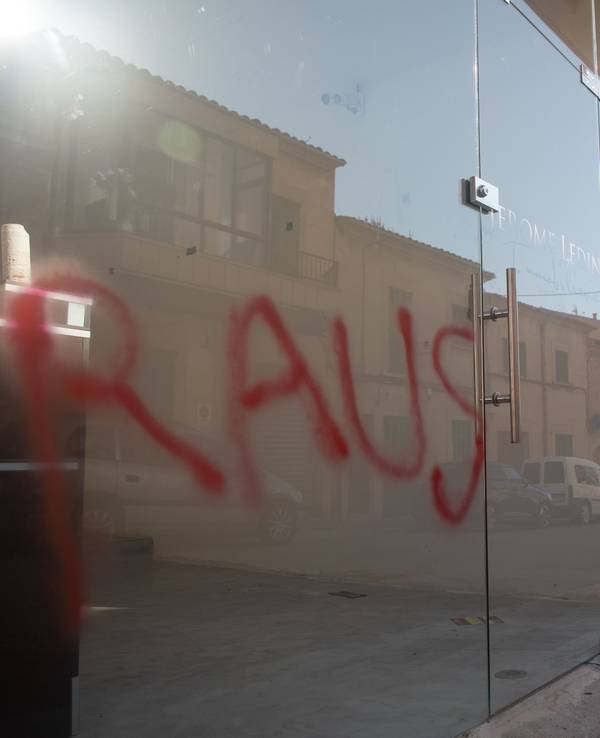 Ein Graffiti mit der Aufschrift „Raus“ ist am Fenster eines Immobilienbüros in Santanyi auf Mallorca zu sehen. Unbekannte haben deutschenfeindliche Sprüche auf Autos und Geschäfte in dem kleinen Ort Santanyi auf Mallorca gesprüht.