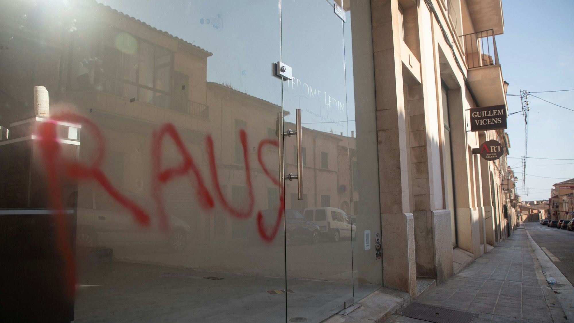 Ein Graffiti mit der Aufschrift „Raus“ ist am Fenster eines Immobilienbüros in Santanyi auf Mallorca zu sehen. Unbekannte haben deutschenfeindliche Sprüche auf Autos und Geschäfte in dem kleinen Ort Santanyi auf Mallorca gesprüht.
