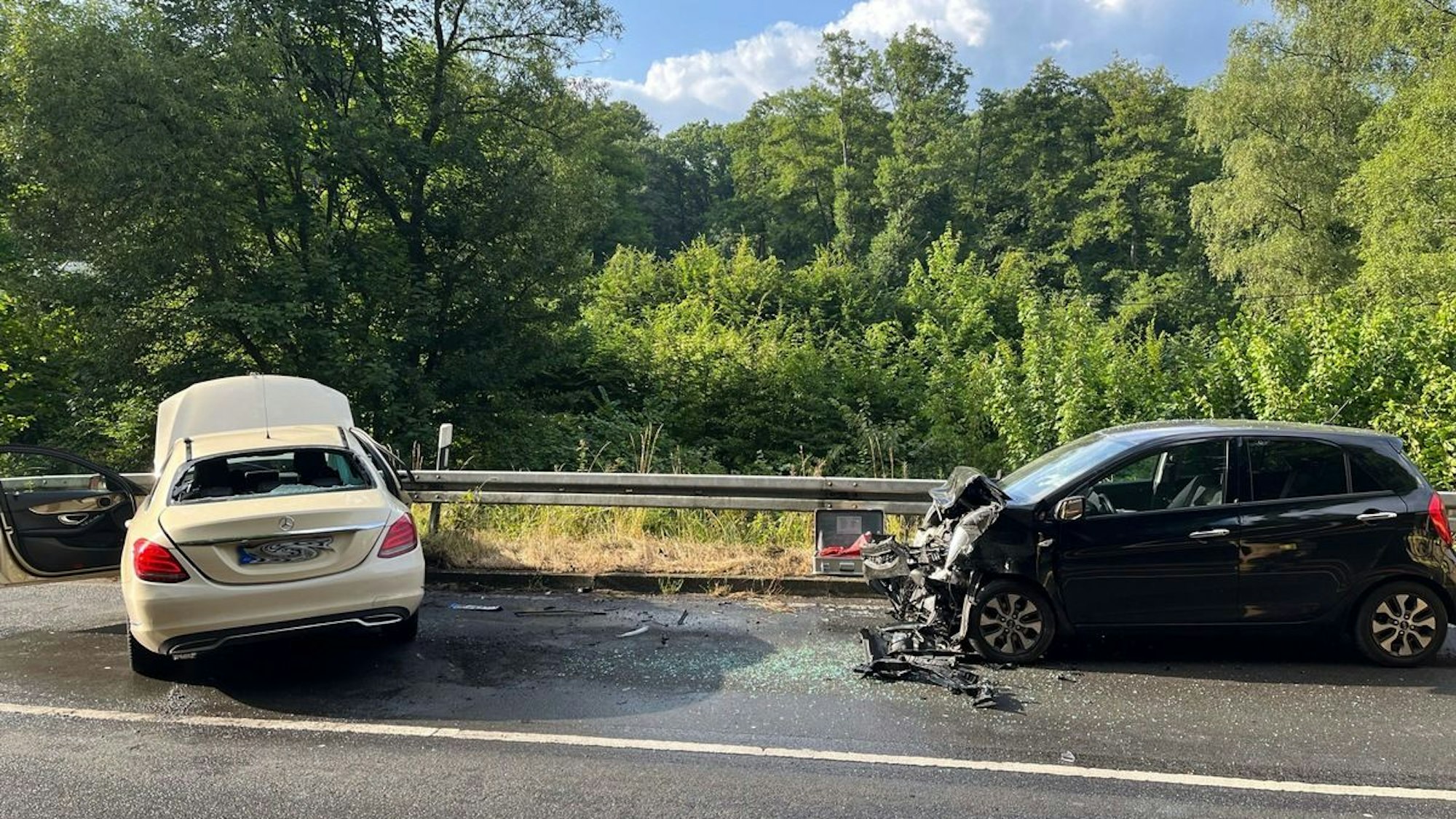 Zwei verunfallte Autos stehen am Straßenrand, die Feuerwehr ist vor Ort.