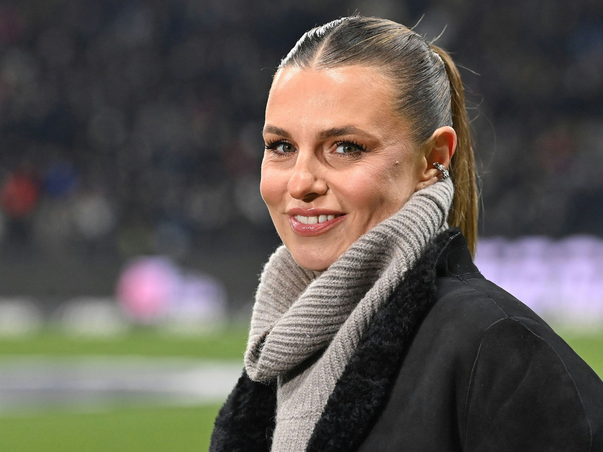 Laura Wontorra lächelt im Stadion in die Kamera.