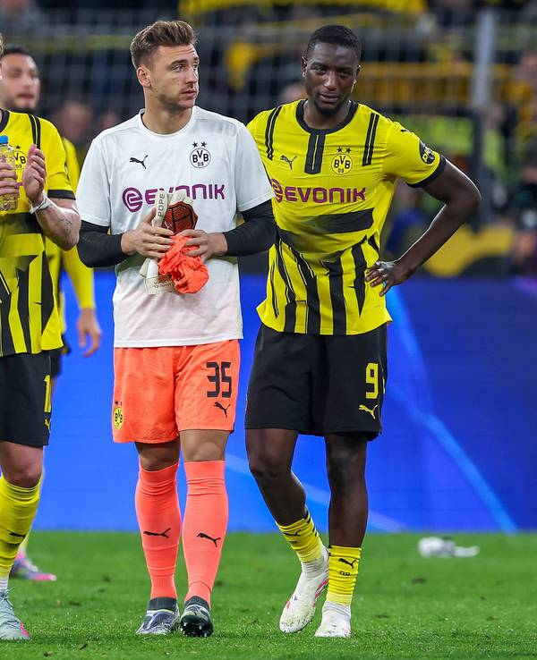 Marcel Lotka geht zwischen Julian Brandt und Serhou Guirassy über den Rasen im Signal-Iduna-Park.