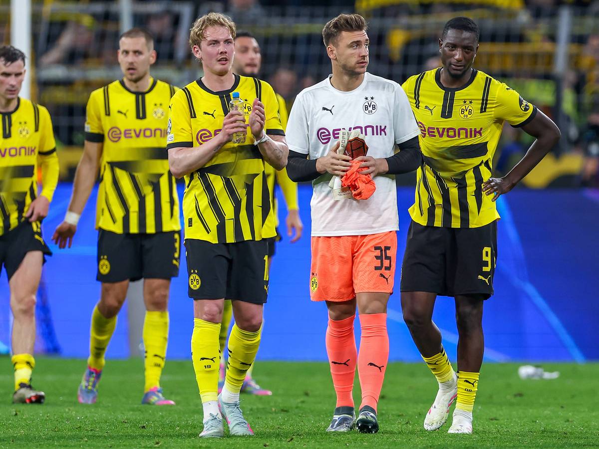 Marcel Lotka geht zwischen Julian Brandt und Serhou Guirassy über den Rasen im Signal-Iduna-Park.