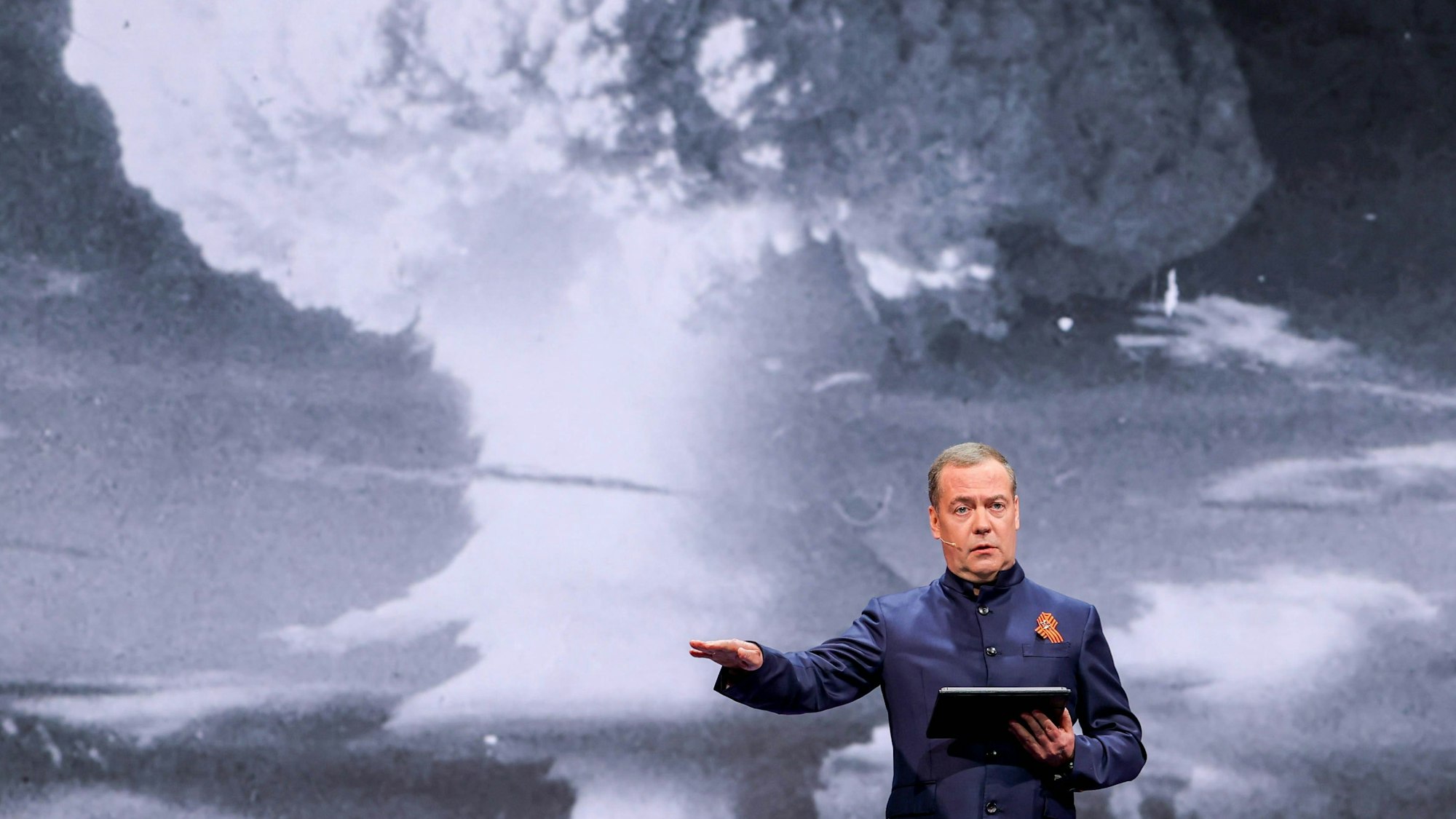 Russlands Ex-Präsident Dmitri Medwedew posiert bei einem Vortrag vor einem Atompilz.