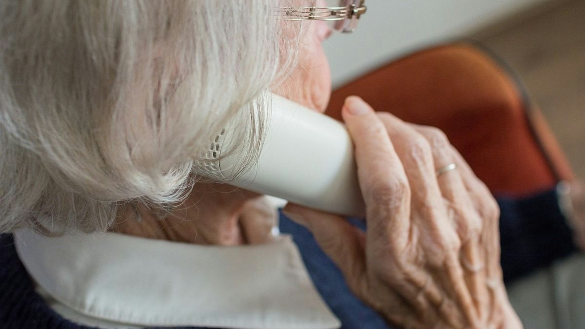 Abbildung einer Seniorin am Telefon, die Opfer von Betrügern geworden ist, die sich als Bankmitarbeiter oder Polizisten ausgeben.