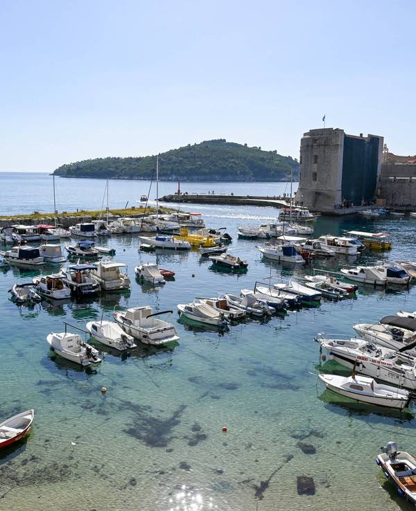 Boote liegen an Stegen vertäut im Wasser, im Hintergrund ein Burgturm