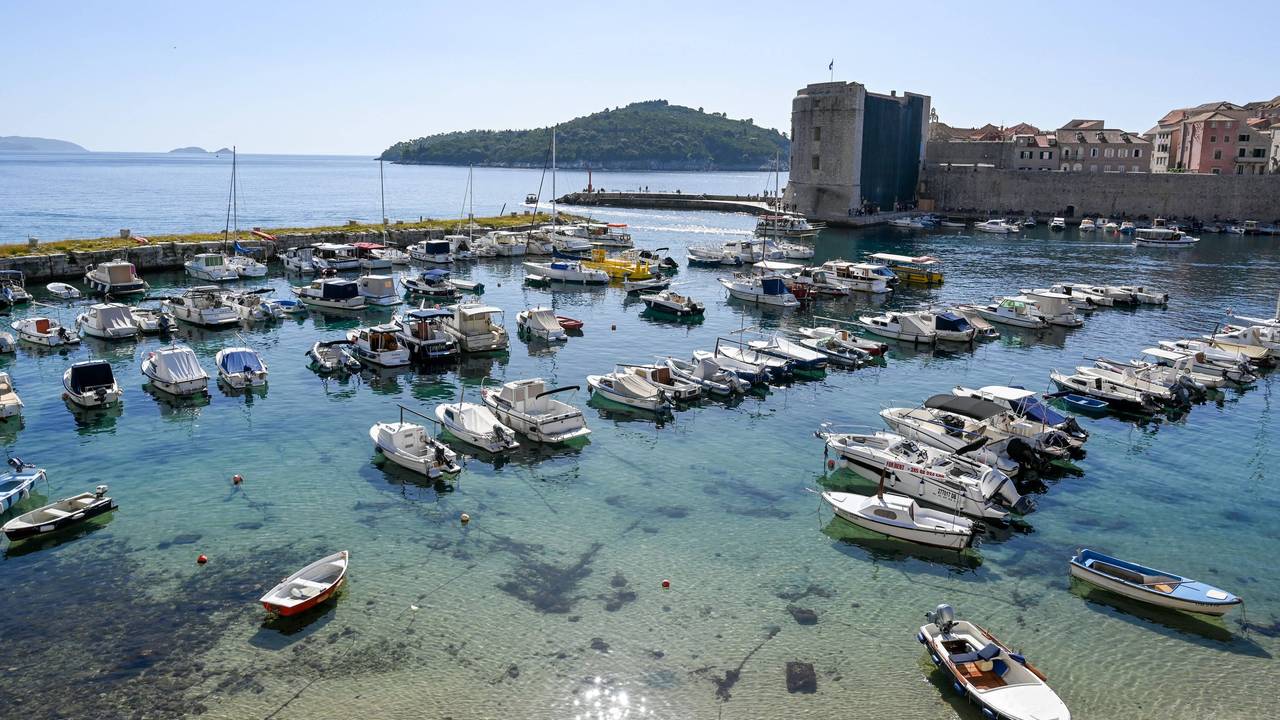 Boote liegen an Stegen vertäut im Wasser, im Hintergrund ein Burgturm