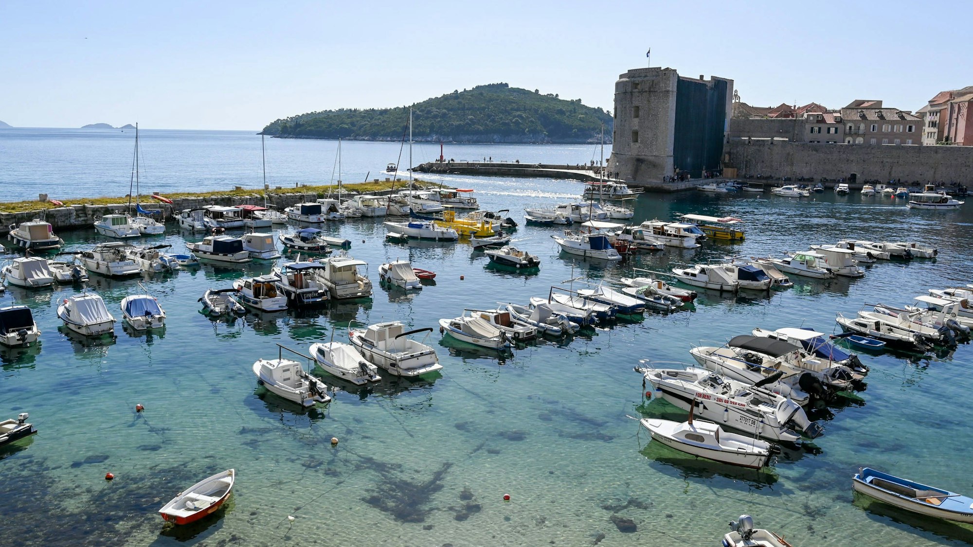 Boote liegen an Stegen vertäut im Wasser, im Hintergrund ein Burgturm