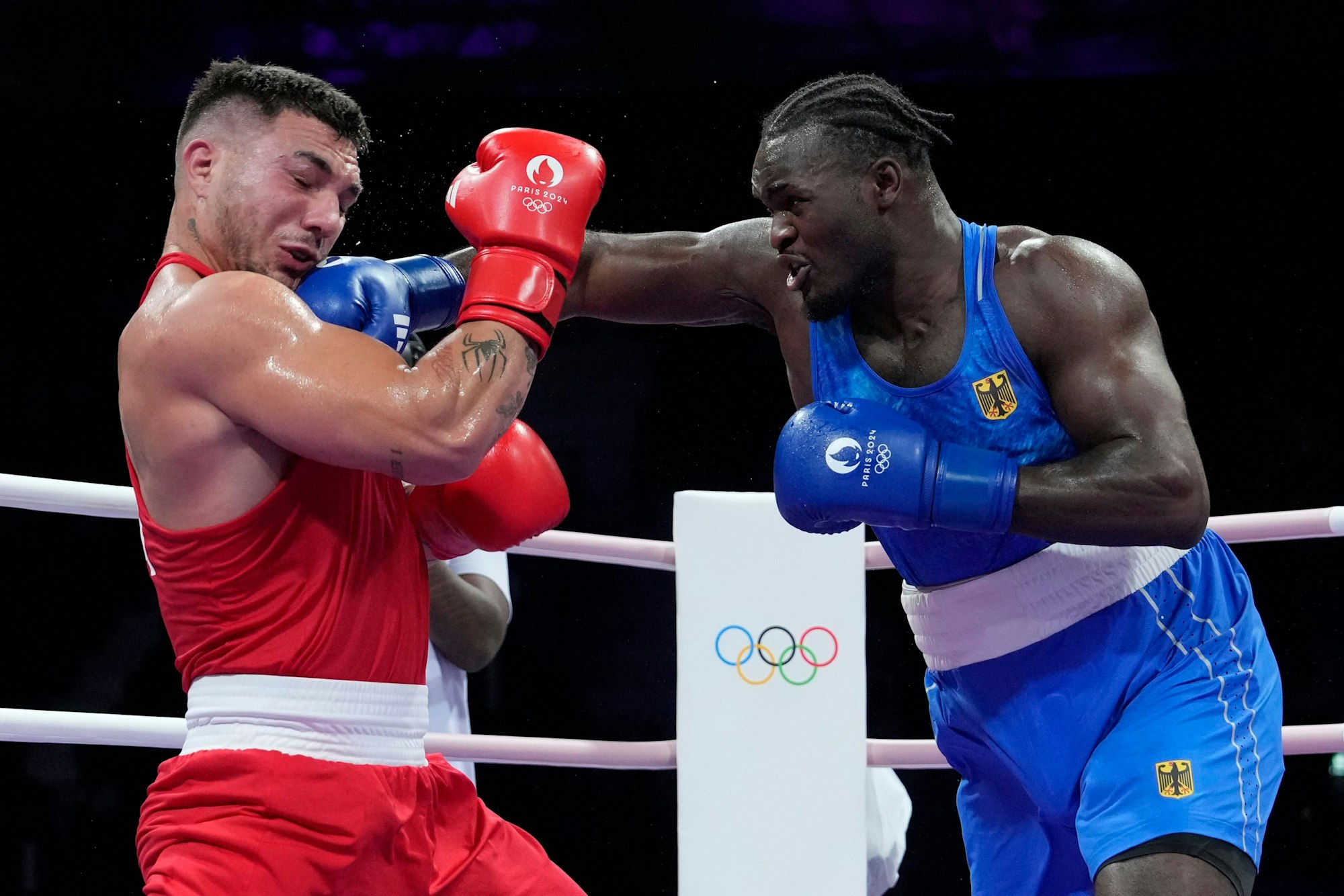Germany's Nelvie Tiafack hits Italy's Diego Lenzi in their men's +92 kg quarterfinal boxing match at the 2024 Summer Olympics, Friday, Aug. 2, 2024, in Paris, France. (AP Photo/Ariana Cubillos)