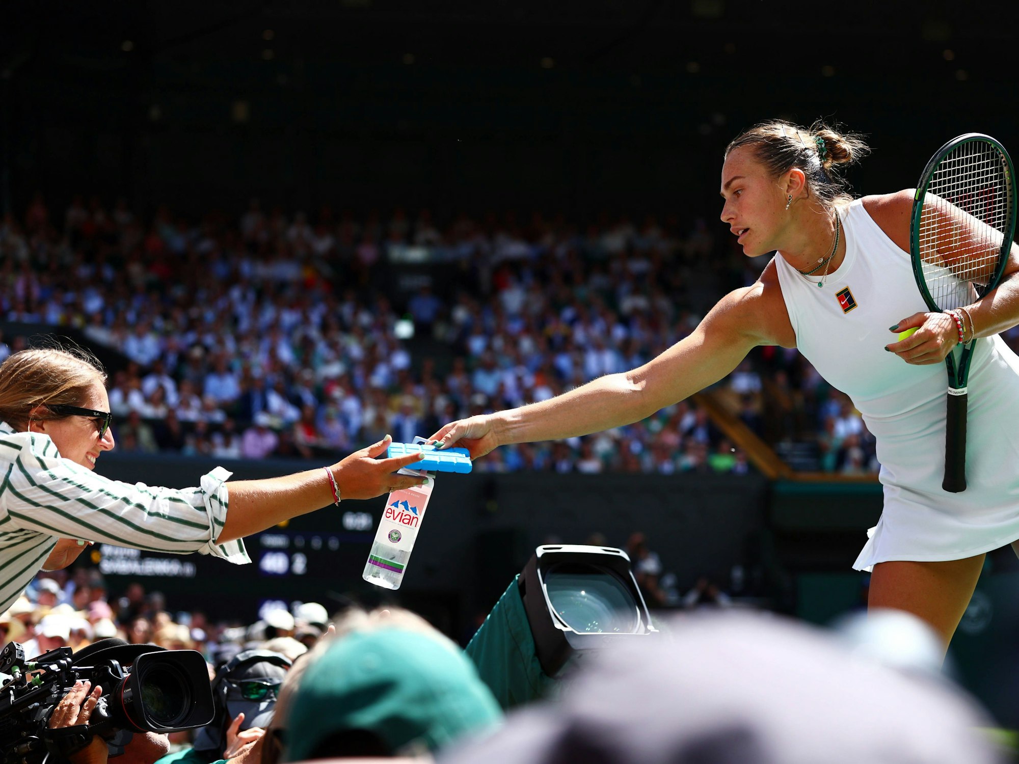 Aryna Sabalenka reicht Wasser und ein Kühlpack.