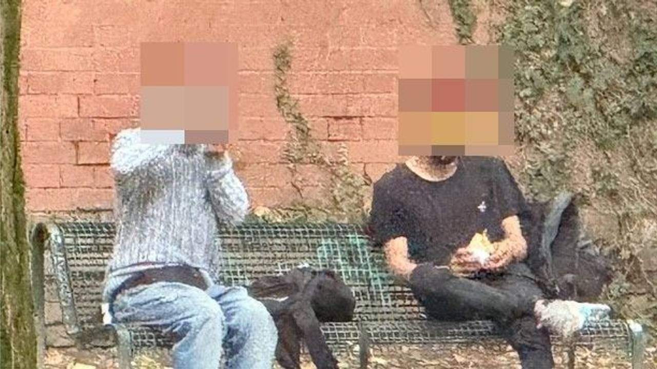 Zwei Männer sitzen auf einer Bank und rauchen Crack.