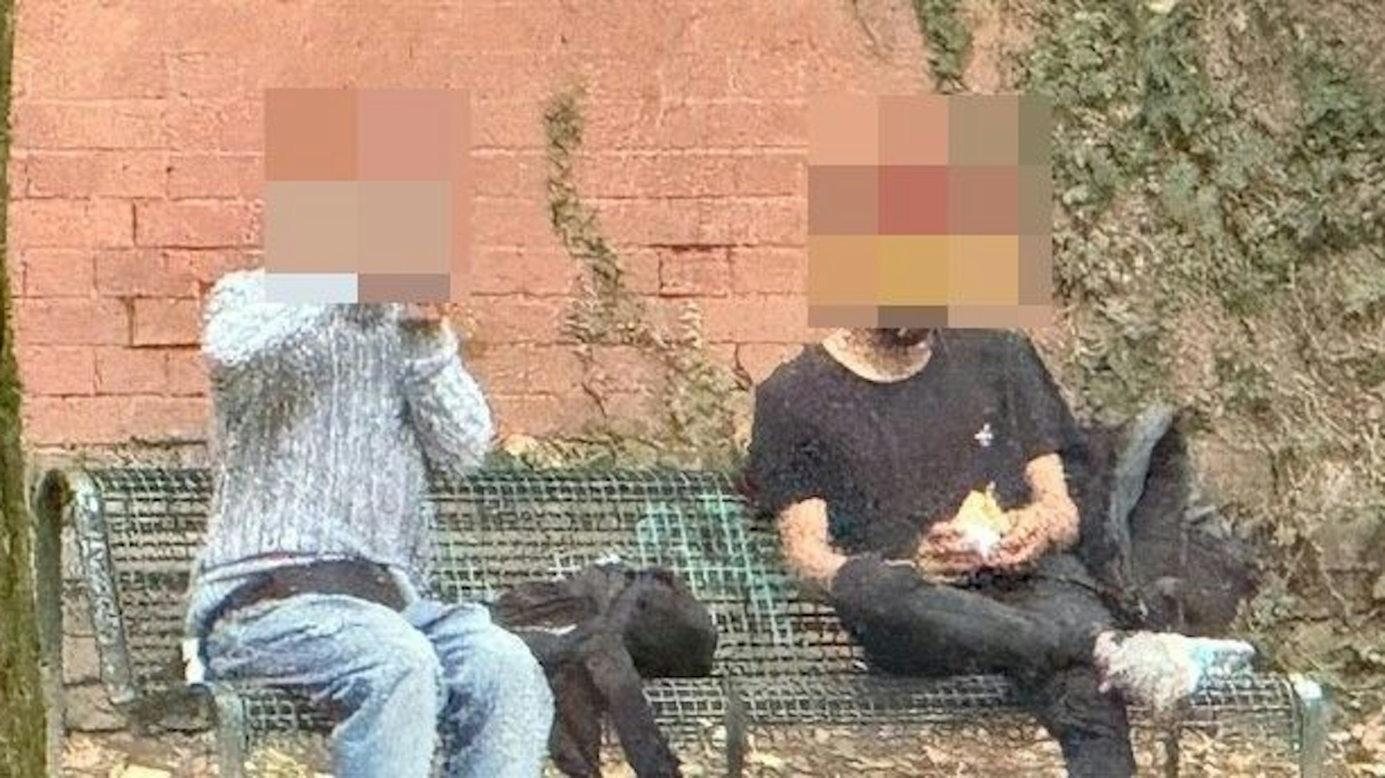 Zwei Männer sitzen auf einer Bank und rauchen Crack.