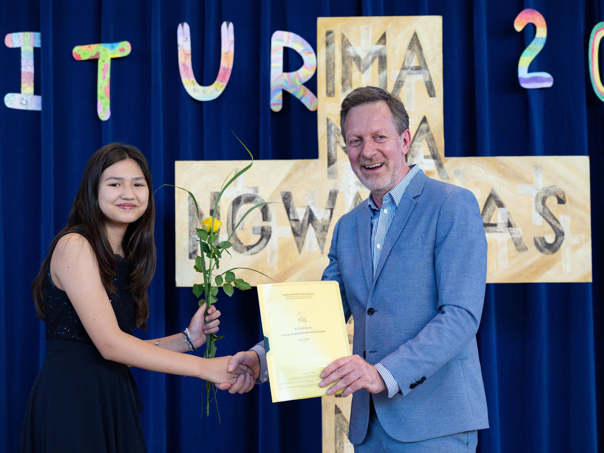 Lina Heider erhält mit gerade einmal elf Jahren ihr Abschlusszeugnis von Christoph Oldeweme, Schulleiter des Erzbischöflichen Mädchen-Gymnasium Sankt-Adelheid.
