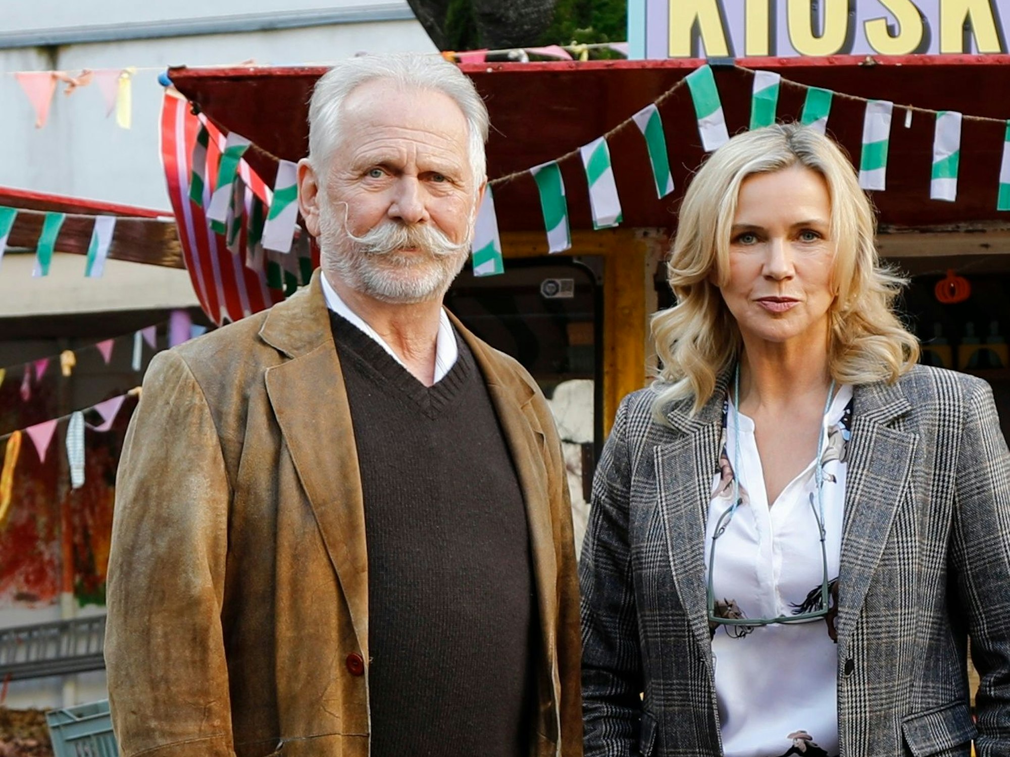 Ein Mann mit Schnäuzer steht neben einer Frau.