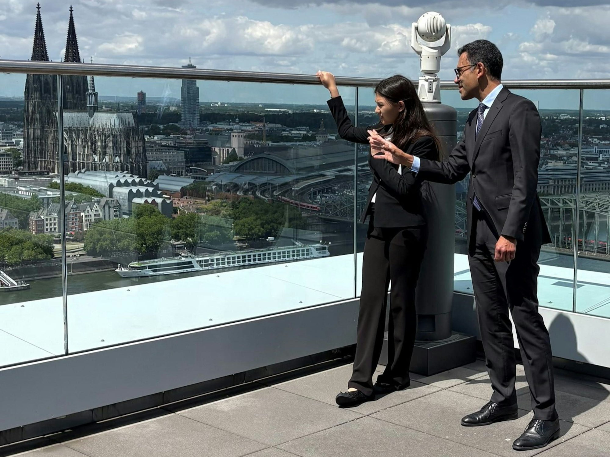 Harry Zumaqué, Leiter für Geschäftsentwicklung und KI-Strategie bei Lanxess, zeigt Lina Heider, der Gewinnerin der Schüleraktion „Meine Position ist spitze“ und Deutschlands jüngste Abiturientin, das Standortumfeld rund um den Lanxess-Tower am Kennedyufer.