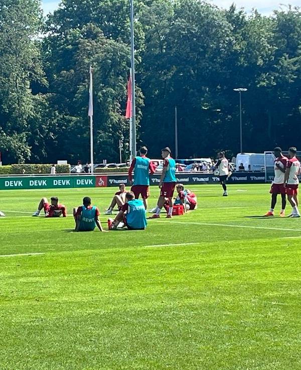 Einige FC-Profis sitzen nach der Laufeinheit erschöpft auf dem Rasen.