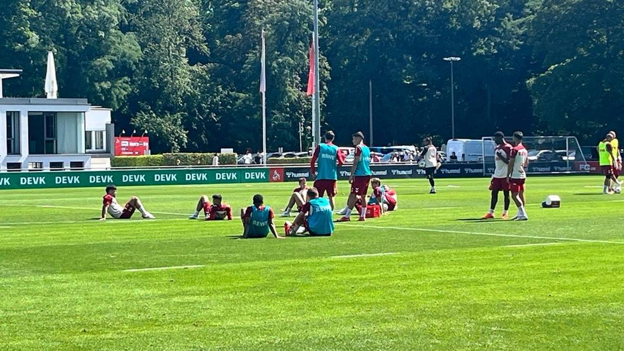 Einige FC-Profis sitzen nach der Laufeinheit erschöpft auf dem Rasen.