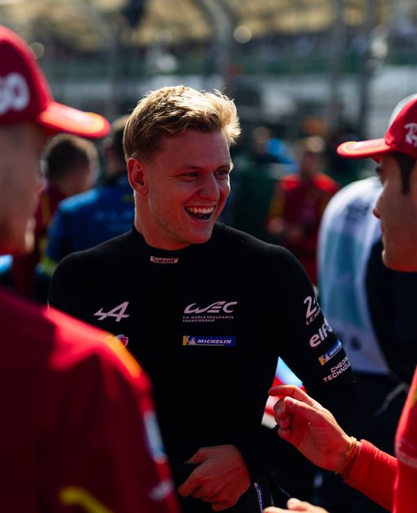 Mick Schumacher lacht im Gespräch mit Rennfahrerkollegen.