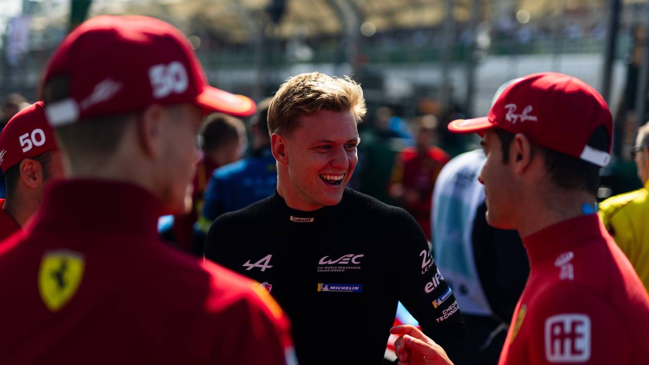 Mick Schumacher lacht im Gespräch mit Rennfahrerkollegen.
