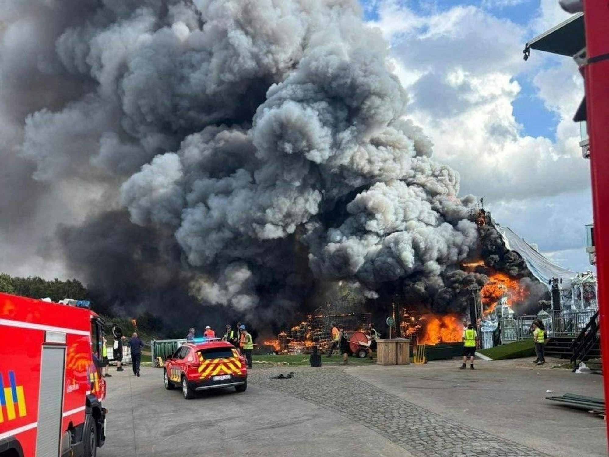 Einsatzkräfte und Fahrzeuge der Feuerwehr stehen vor einem Brand.