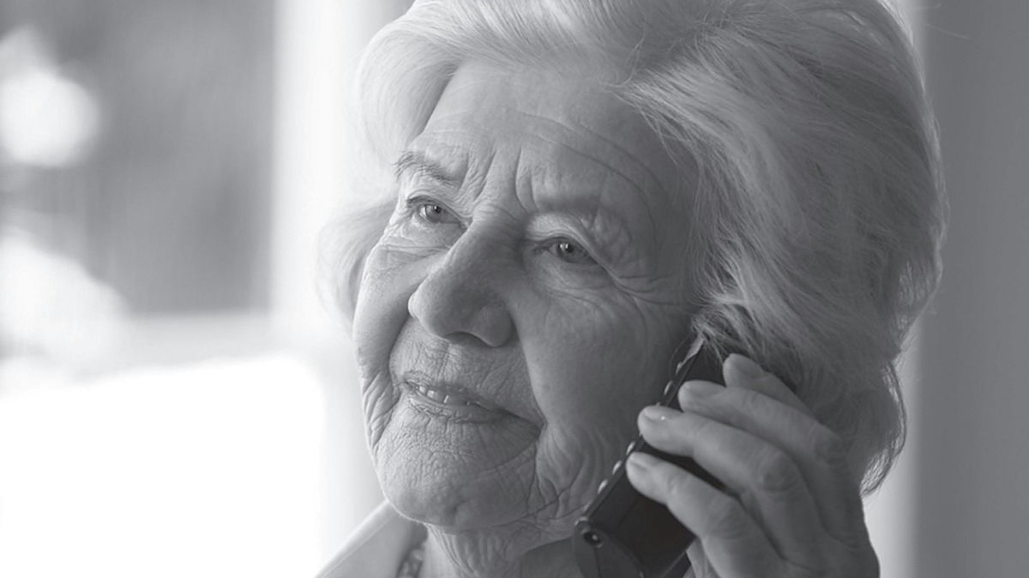 Eine ältere Dame telefoniert und schaut besorgt.
