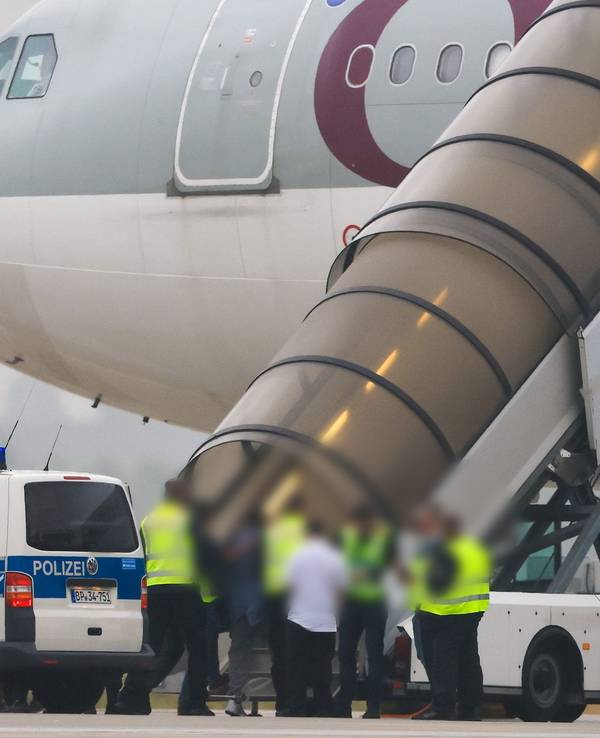 Menschen besteigen ein Flugzeug der Qatar Airways, vor dem Fahrzeuge der Bundespolizei stehen auf dem Vorfeld am Flughafen Leipzig/Halle.