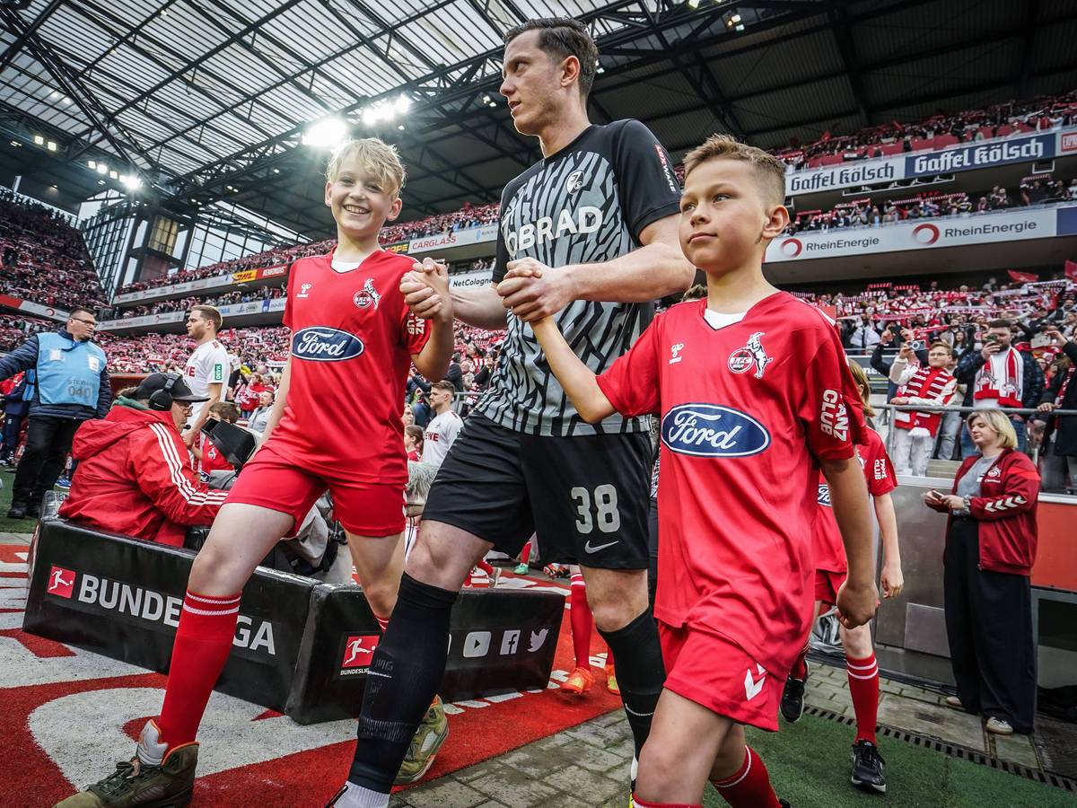 Michael Gregoritsch läuft mit zwei Einlaufkindern ins Rhein-Energie-Stadion ein.