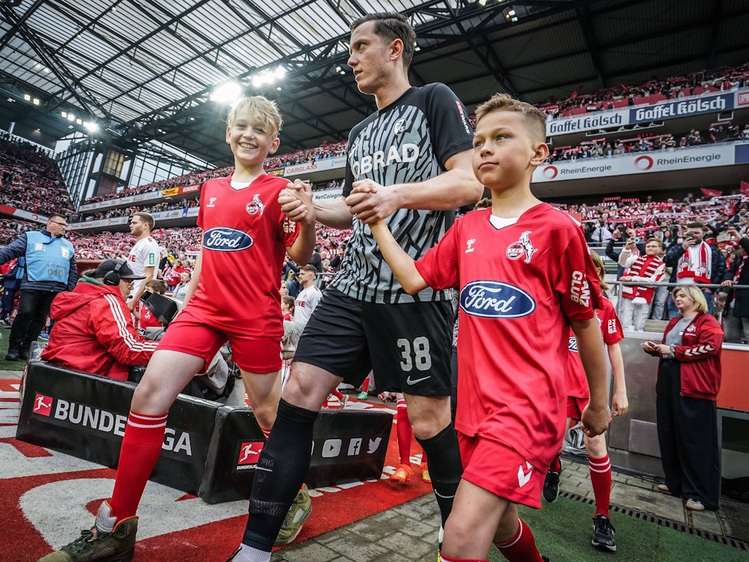 Michael Gregoritsch läuft mit zwei Einlaufkindern ins Rhein-Energie-Stadion ein.