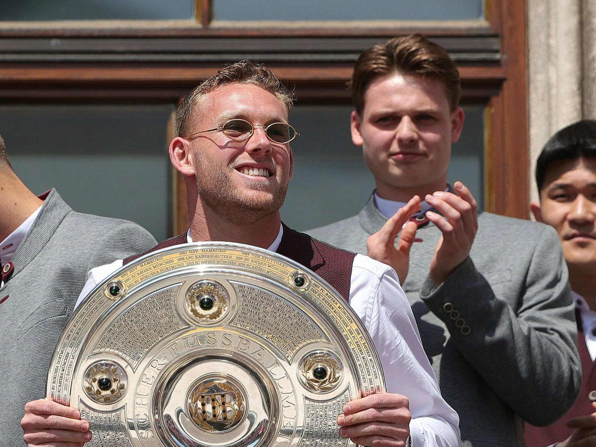 Daniel Peretz hält auf dem Ratshausbalkon die Meisterschale hoch, im Hintergrund applaudiert Jonas Urbig.