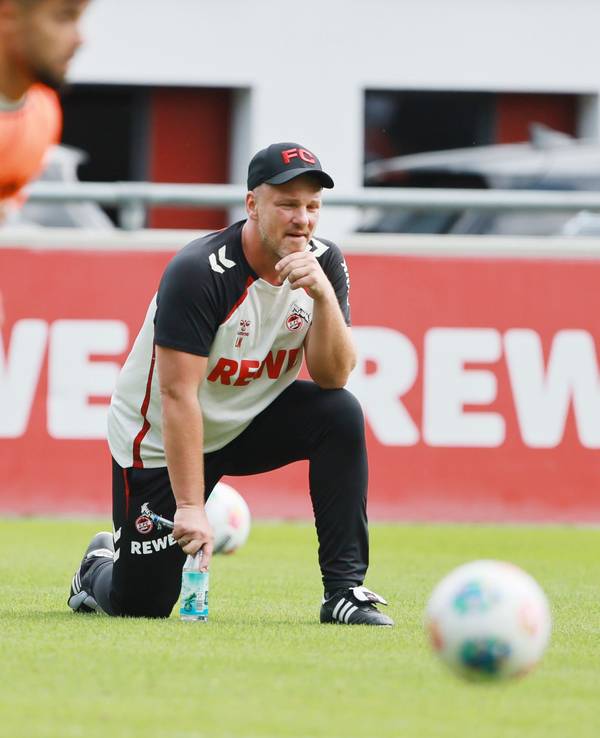 Lukas Kwasniok hockt mit einem Knie auf dem Trainingsplatz des 1. FC Köln.