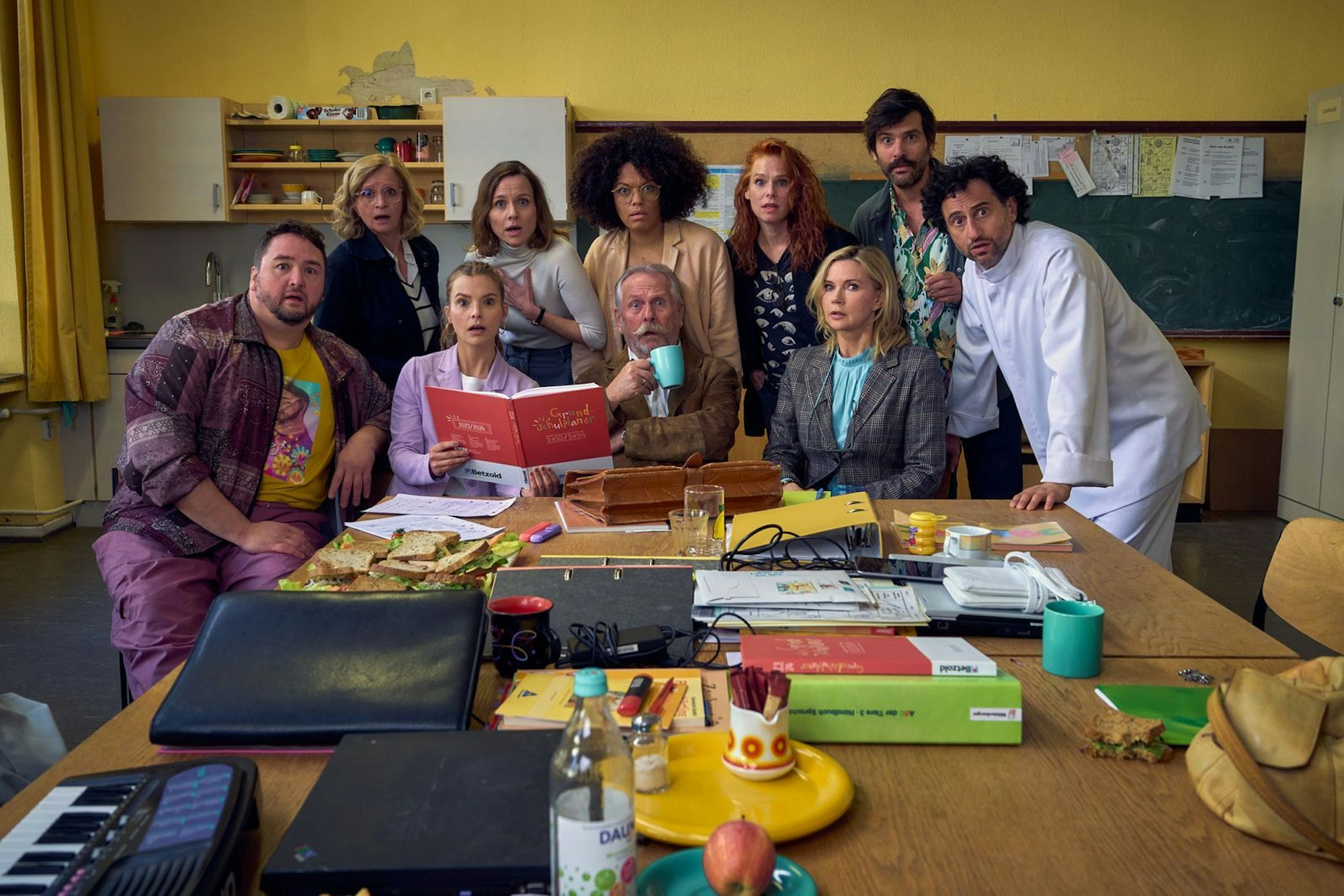 Die hoch gelobte Impro-Serie „Andere Eltern“ über eine Kita-Gründung geht einige Jahre später als Film und in der Grundschule weiter. Das Ensemble des ZDF-Films umfasst unerwartete Stars wie Veronica Ferres (dritte von rechts) als Direktorin oder Ex-Höhner-Sänger Henning Krautmacher (Mitte vorn). (Bild: ZDF und © Frank Dicks)