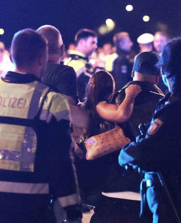 Ersthelfer und Polizisten sowie Polizistinnen begleiten eine verletzte Person zu den Sanitätern und Sanitäterinnen auf einer Brücke.