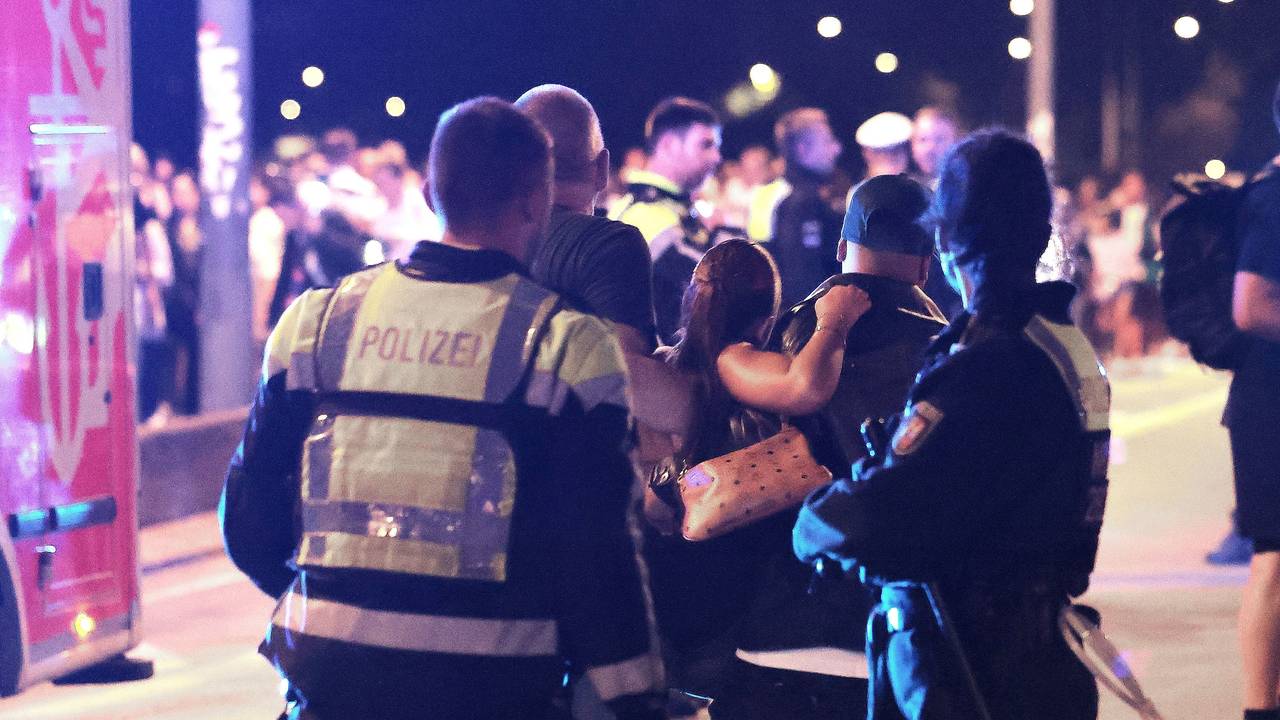 Ersthelfer und Polizisten sowie Polizistinnen begleiten eine verletzte Person zu den Sanitätern und Sanitäterinnen auf einer Brücke.
