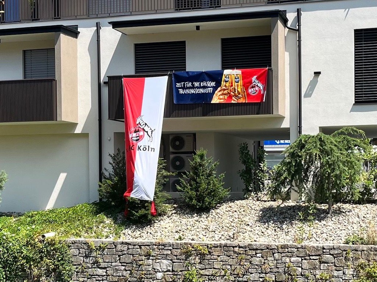 Balkon mit FC-Fahne und Gaffel-Werbung.