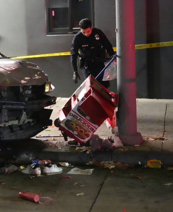 Ein demoliertes Fahrzeug steht auf dem Bürgersteig, nachdem es in Los Angeles in eine Menschenmenge gerast war. Ein Polizist untersucht den Unfallort.
