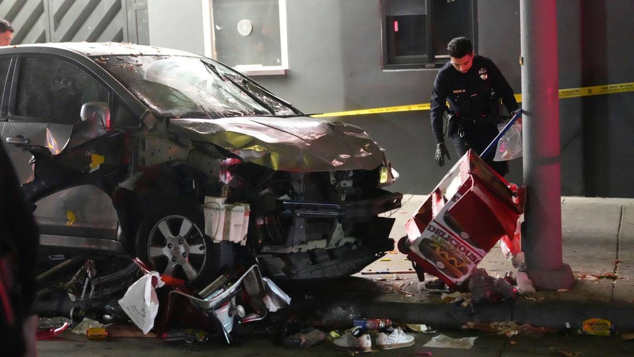 Ein demoliertes Fahrzeug steht auf dem Bürgersteig, nachdem es in Los Angeles in eine Menschenmenge gerast war. Ein Polizist untersucht den Unfallort.