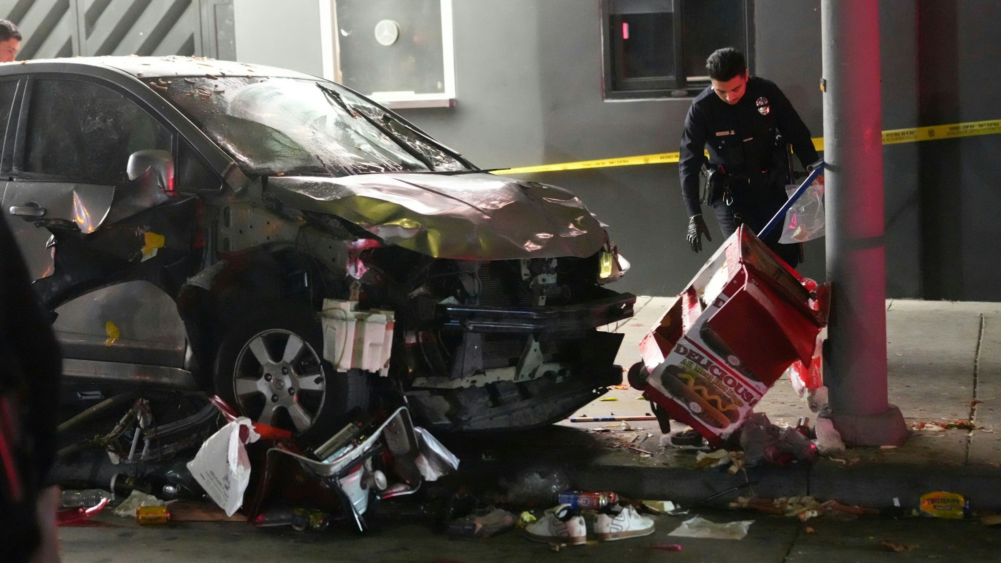 Ein demoliertes Fahrzeug steht auf dem Bürgersteig, nachdem es in Los Angeles in eine Menschenmenge gerast war. Ein Polizist untersucht den Unfallort.