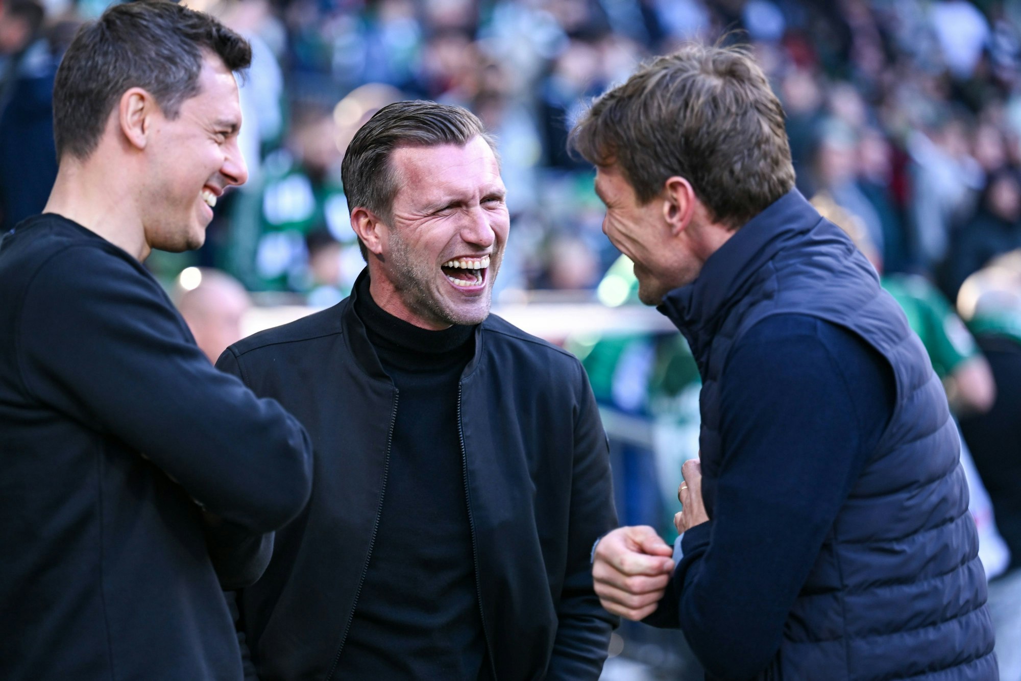 Markus Krösche lacht bei einem Gespräch im Stadion.